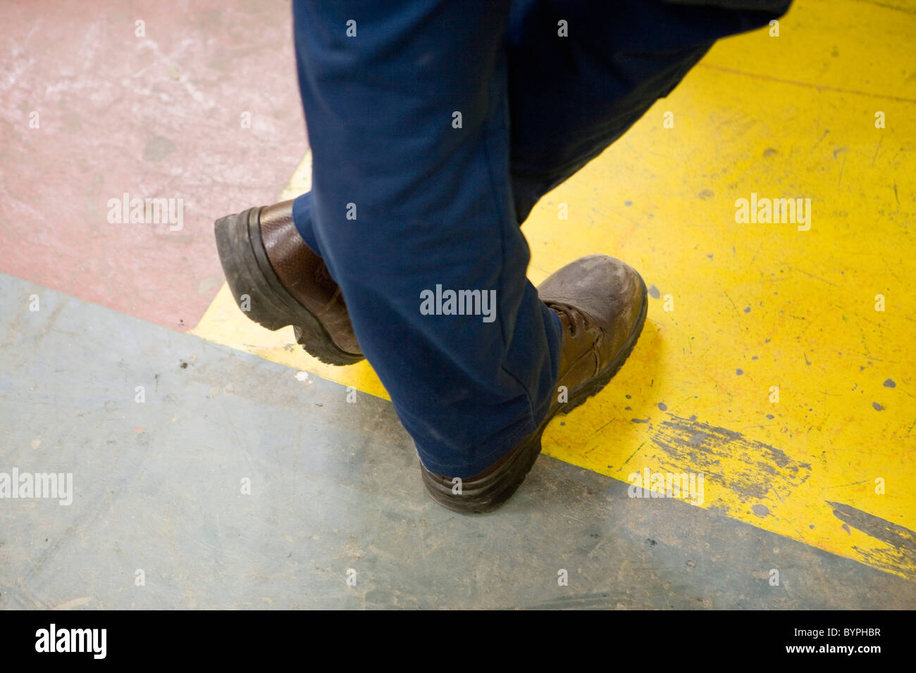 Operaio di fabbrica indossare stivali protettivi, in piedi con le gambe incrociate a caviglia, ritagliato Foto Stock