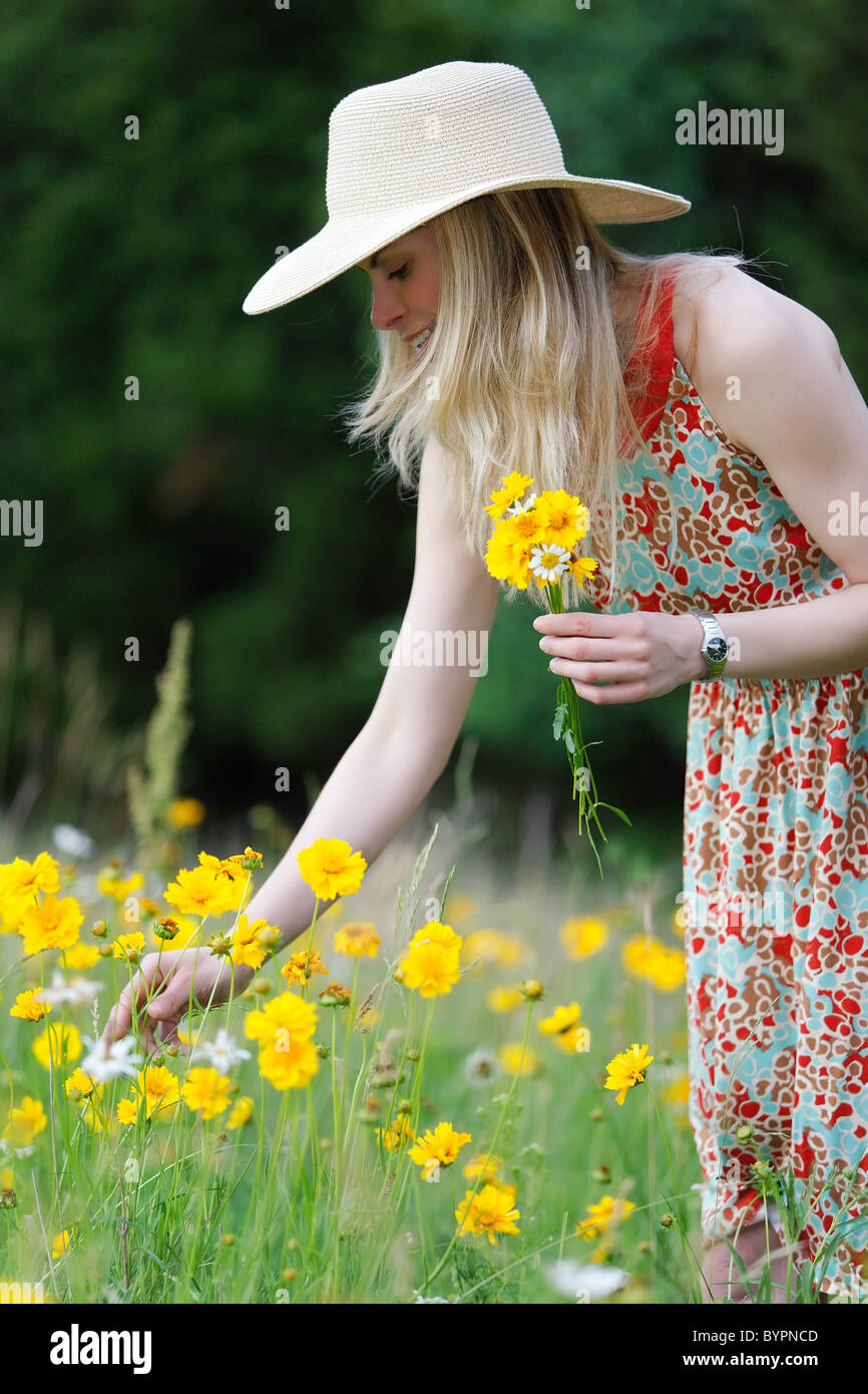Giovane donna in abiti estivi e Hat la raccolta di fiori di campo in un prato, New Jersey Foto Stock
