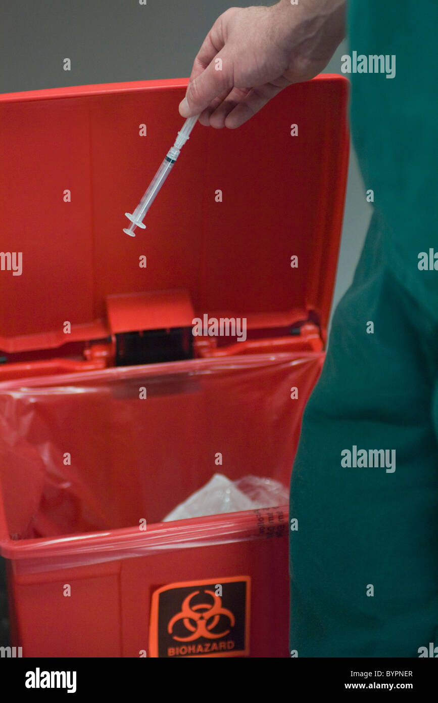 Professionista del healthcare immissione siringa usata in rifiuti pericolosi ricettacolo Foto Stock