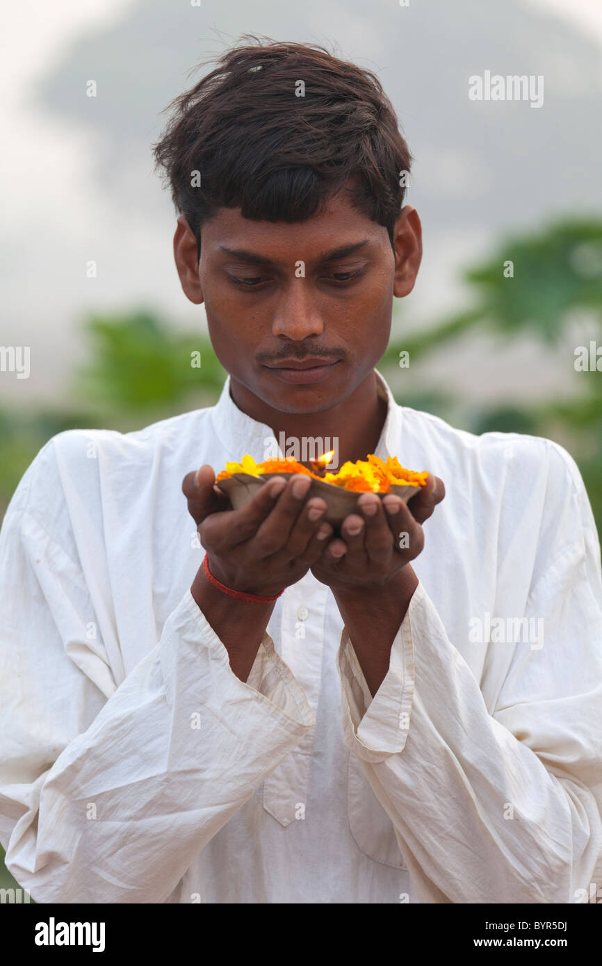 India, Uttar Pradesh, giovane uomo indù tenendo la preghiera della lampada e le calendule Foto Stock