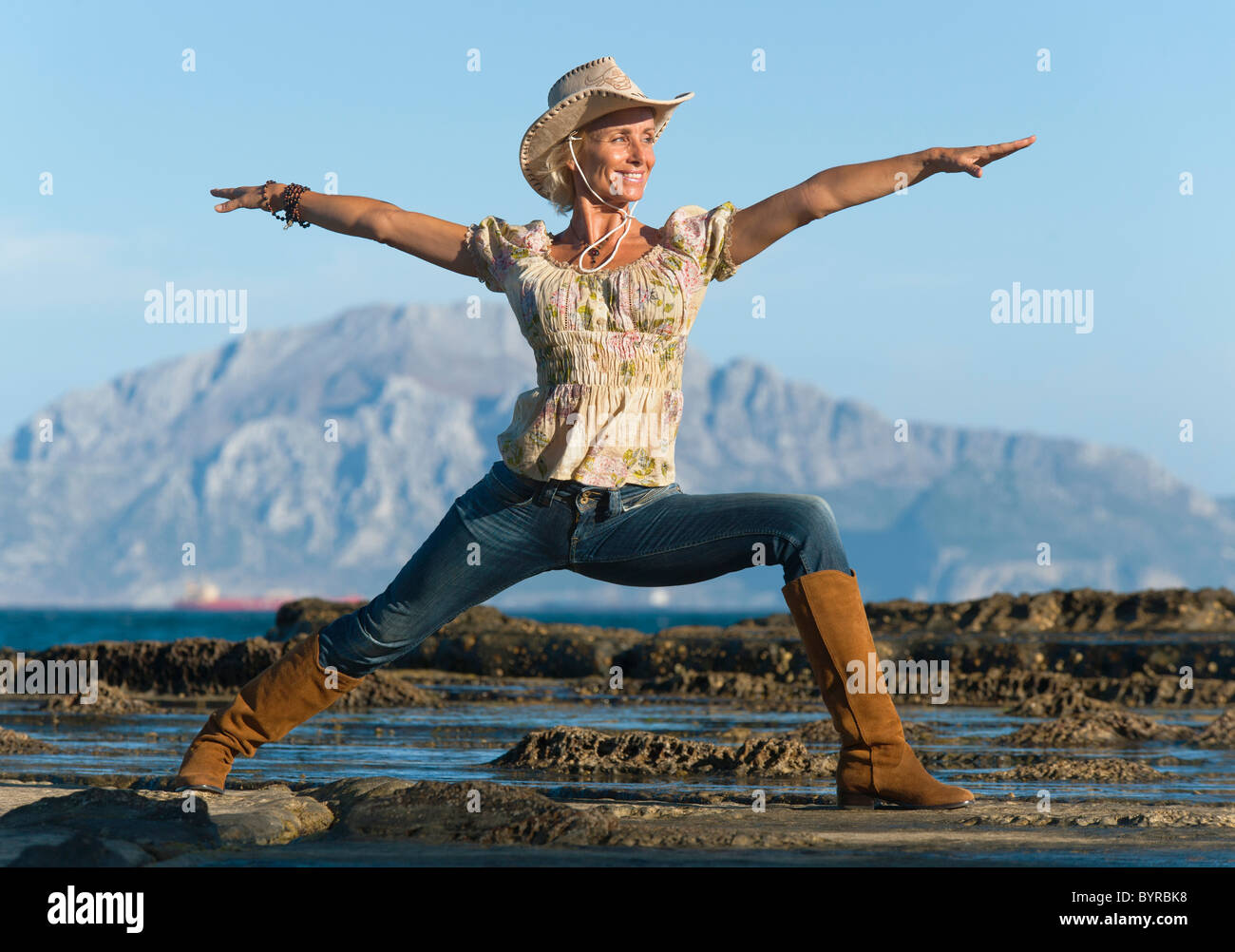 Una donna che indossa un cappello da cowboy facendo un po' di yoga posa in Parque natural del estrecho; Tarifa, Cadice, Andalusia, Spagna Foto Stock