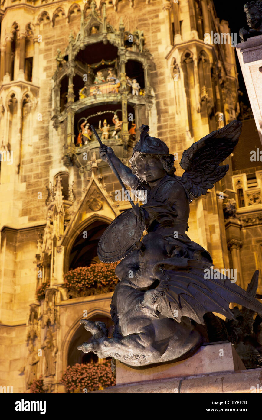 Statua alato con un acceso della torre del municipio e glockenspiel in background di notte; Monaco di Baviera, Germania Foto Stock