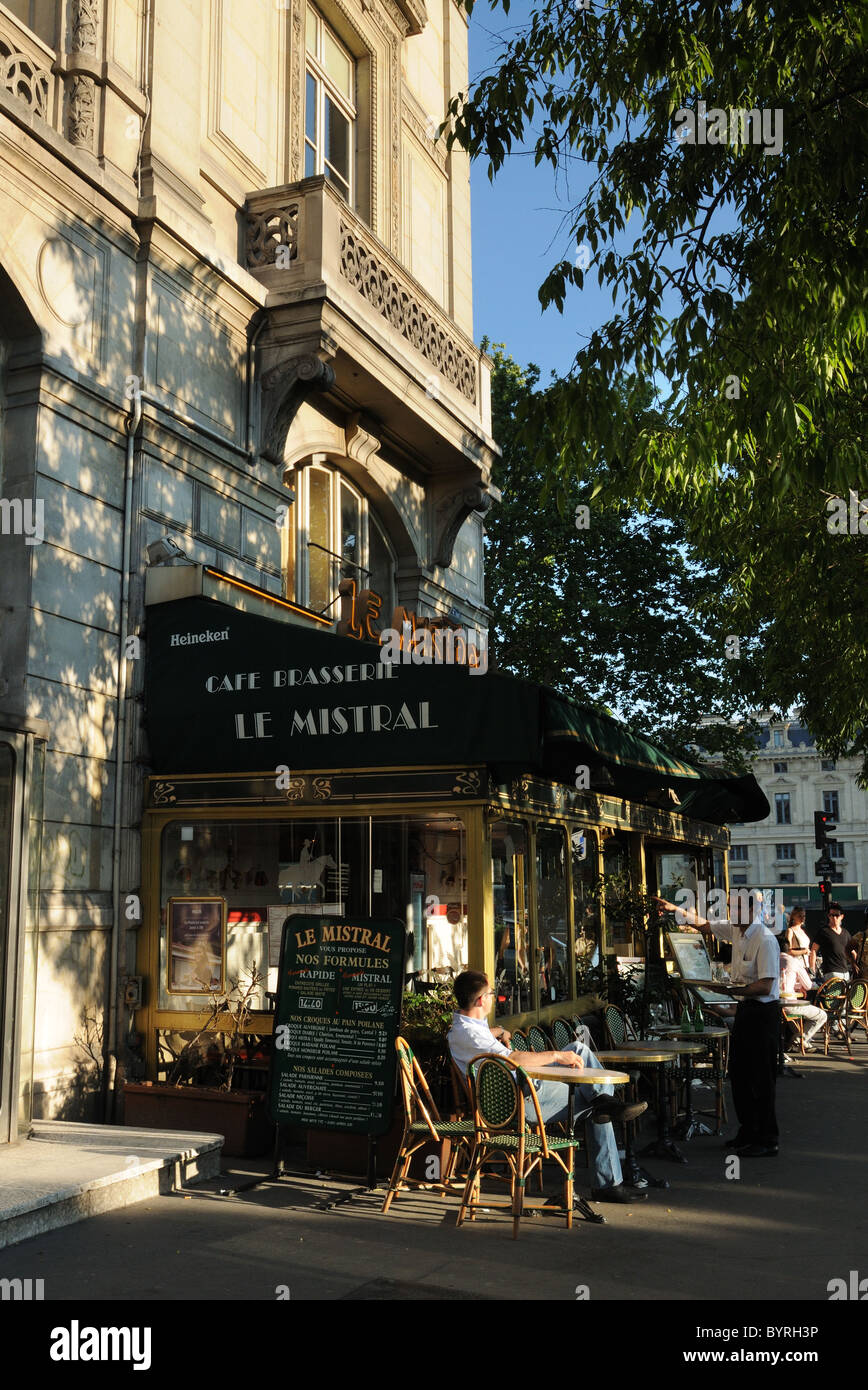 Un uomo seduto al sole al di fuori di un caffè di Parigi, Francia Foto Stock