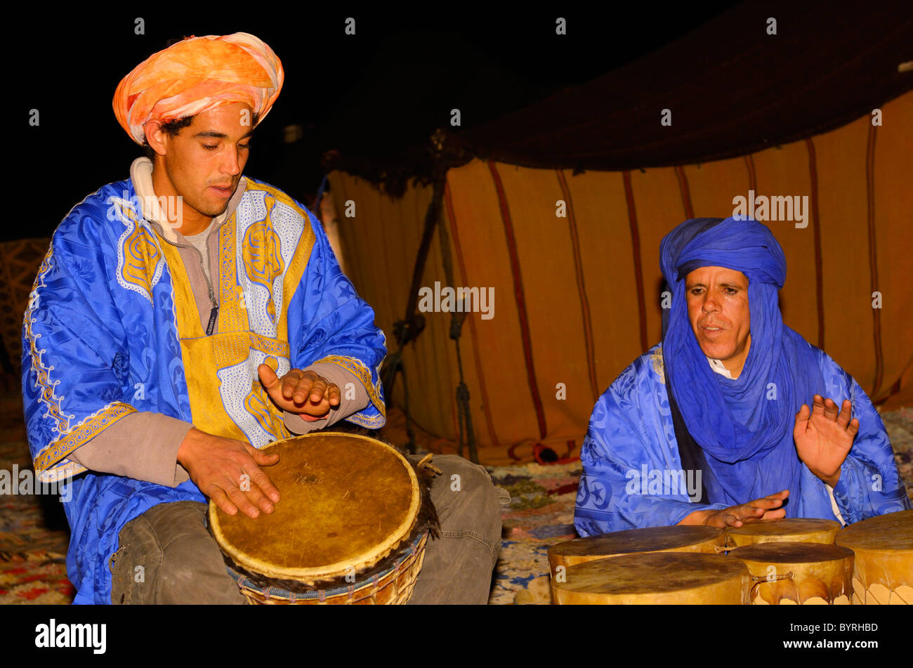 Blu tuareg berbero uomini giocando djembe e tamburi bongo di notte in Erg Chebbi Marocco nel deserto Foto Stock