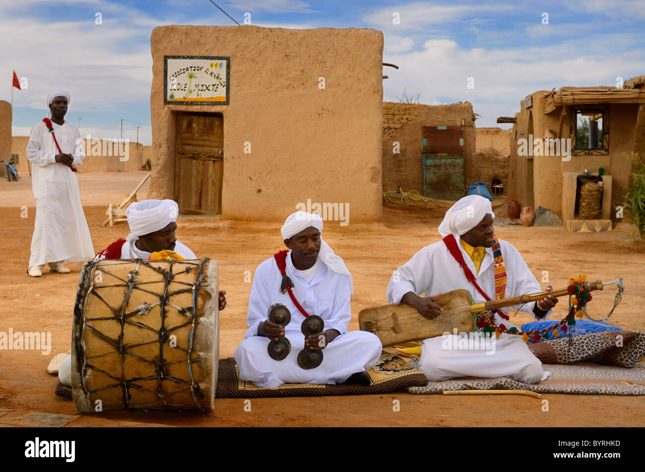 Gnawa music group in bianco turbanti e jellabas seduta e la riproduzione di musica in Khemliya villaggio nel deserto del Marocco del Nord Africa Foto Stock