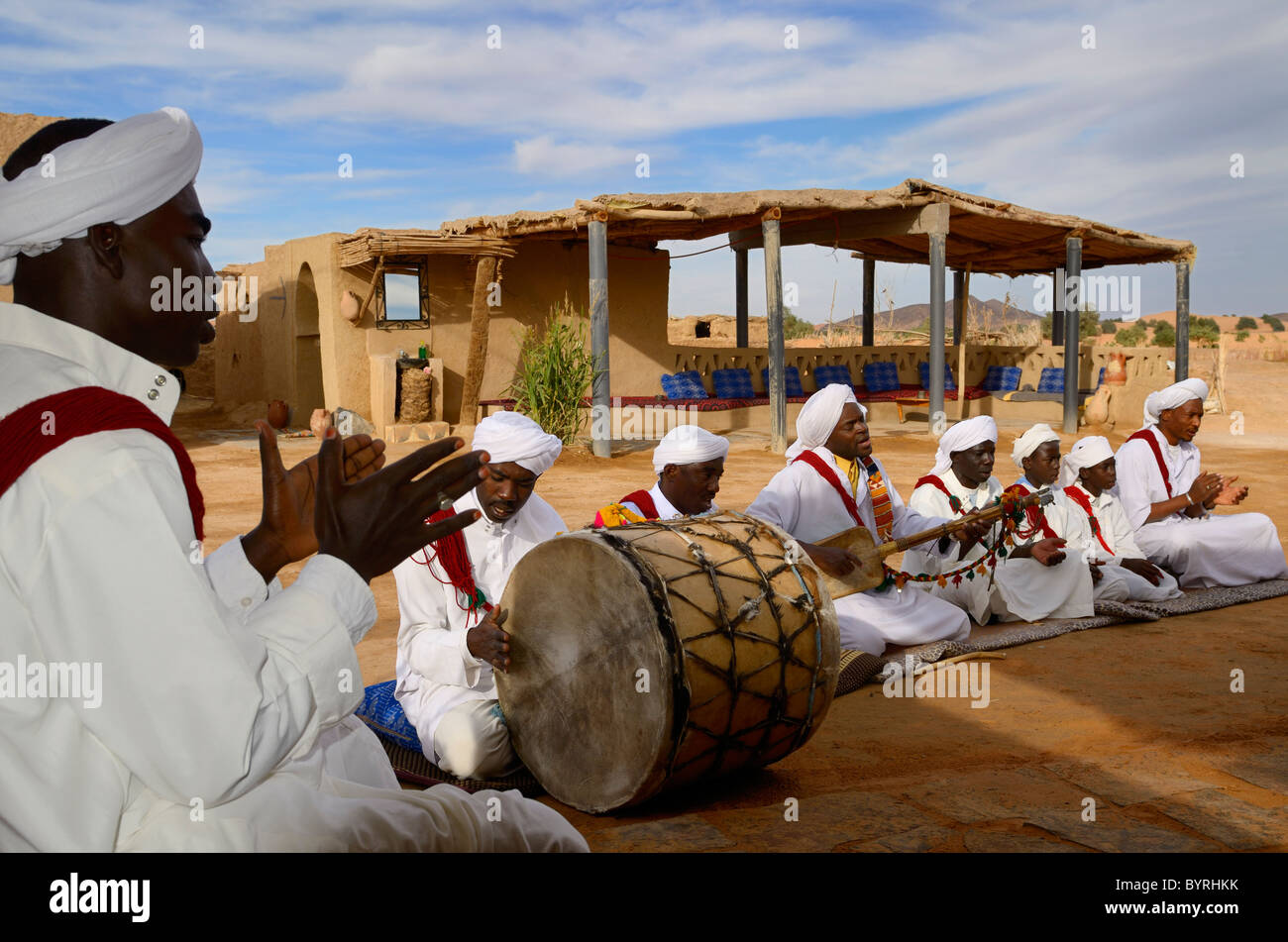 Piccioni du Sable Gnawa music group in bianco turbanti e djellabas suonare il tamburo lato clap liuto gimbri nel villaggio Khemliya Marocco Africa del Nord Foto Stock