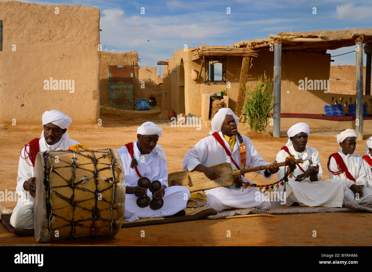 Khemliya gnawa musicisti in bianco turbanti e jellabas giocare mentre è seduto in un villaggio nel deserto khemliya marocco Foto Stock