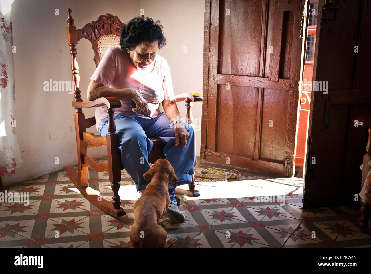 Una donna su una sedia a dondolo con il suo cane, Santiago de Cuba, Cuba, dei Caraibi Foto Stock