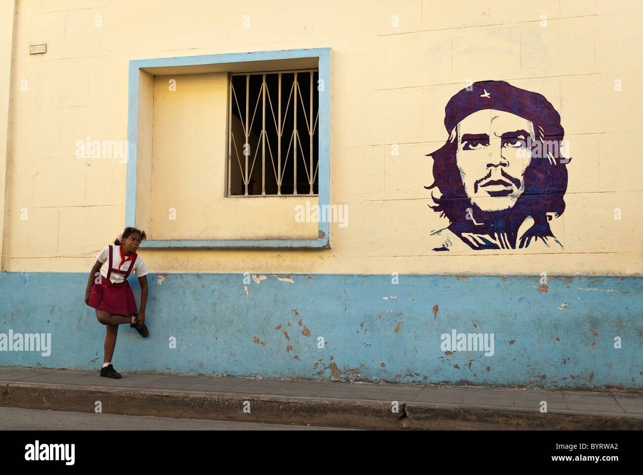 Ragazza in un'uniforme scolastica vicino a un dipinto di Che Guevara, Camaguey, Cuba, dei Caraibi. Foto Stock