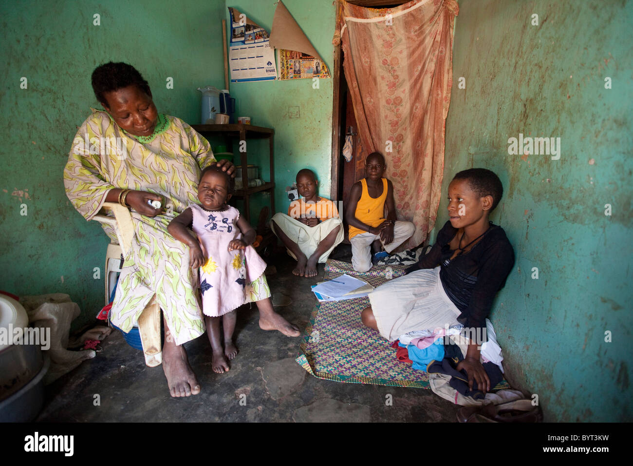 Una famiglia siede in loro una camera casa in citta' interna Kampala, Uganda, Africa orientale. Foto Stock