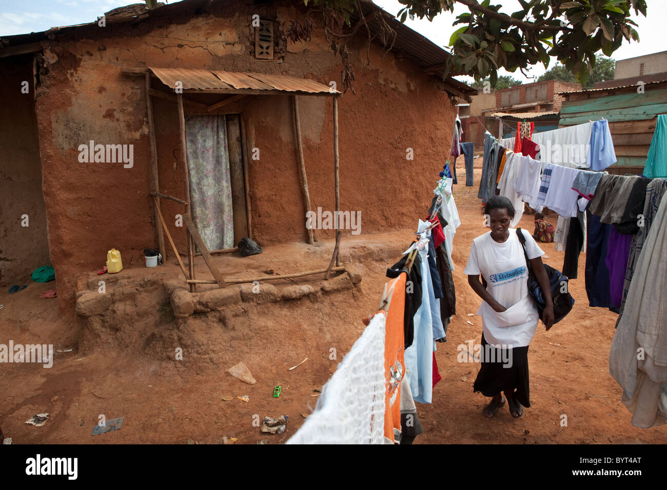 Una comunità operatore sanitario con le ONG merci vivente cammina attraverso una delle baraccopoli di Kampala, in Uganda, in Africa orientale. Foto Stock