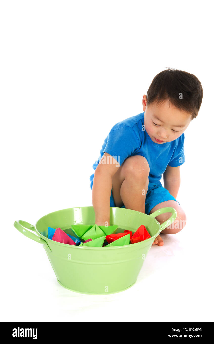 Little Chinese Boy è in corso di riproduzione con barche di carta isolato su bianco Foto Stock