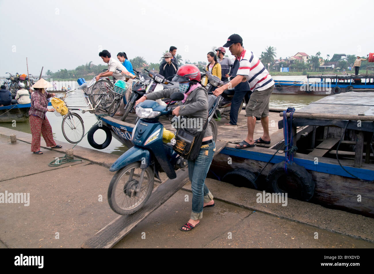 Il Vietnam il caricamento di scooter e biciclette di una chiatta per attraversare il fiume a Hoi An Foto © Julio Etchart Foto Stock
