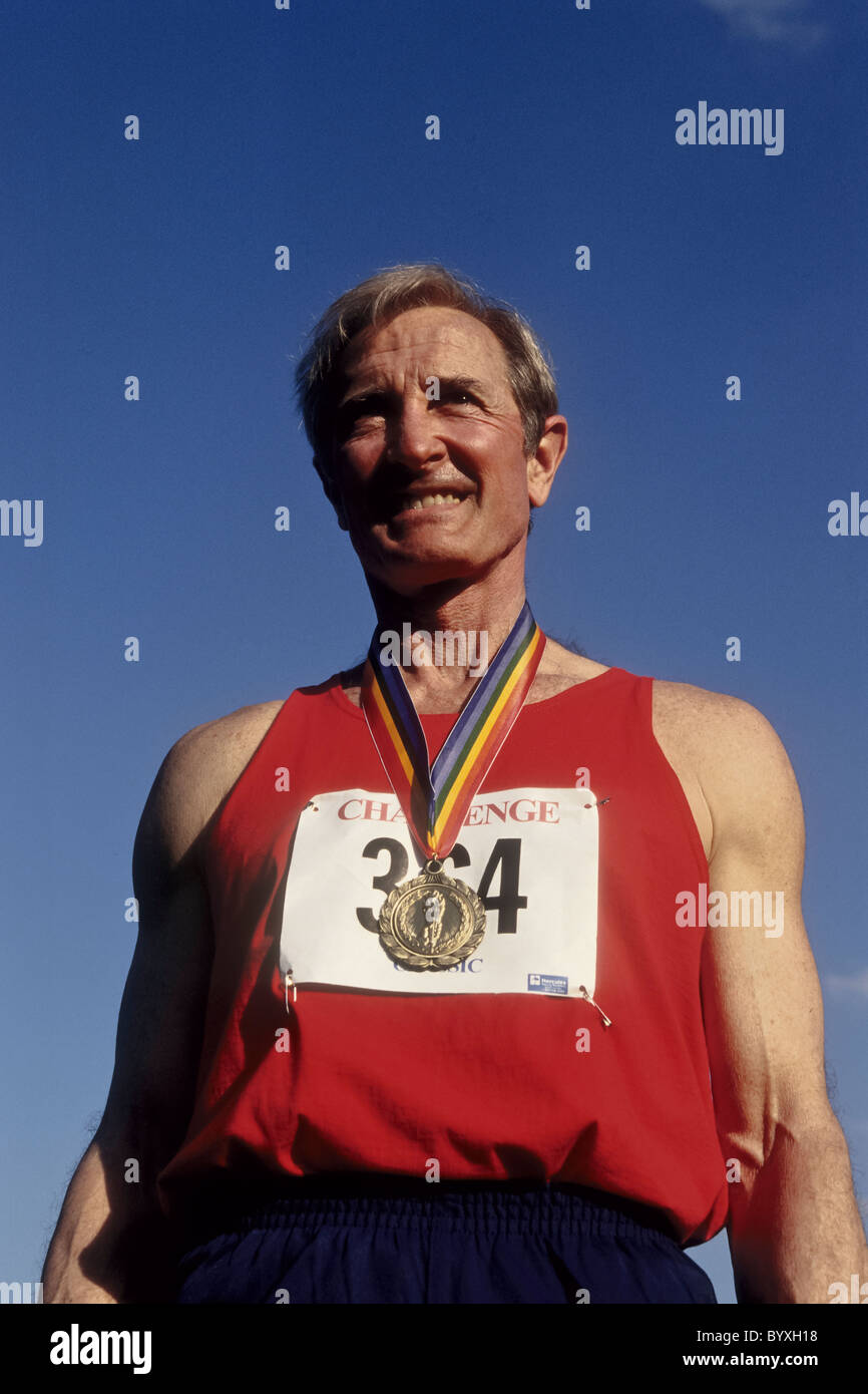 Maschi anziani via e atleta di campo con la sua medaglia d'oro. Foto Stock