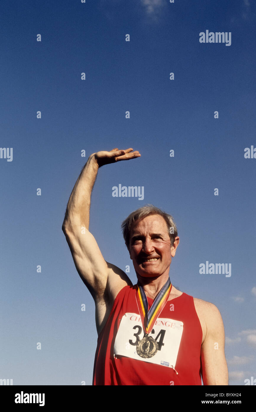 Maschi anziani via e atleta di campo con la sua medaglia d'oro. Foto Stock