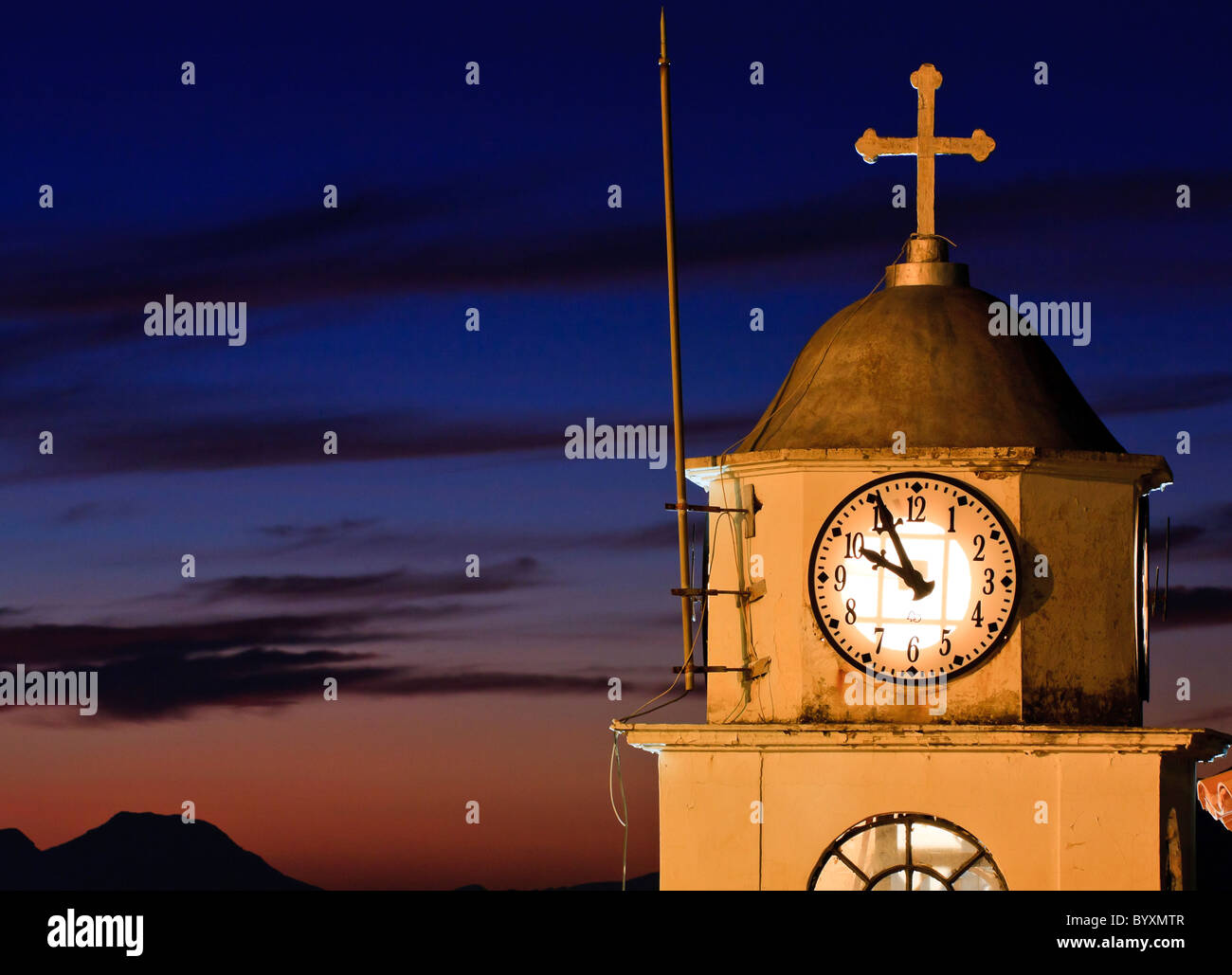 Vecchia chiesa orologio contro il tramonto in Grecia Foto Stock