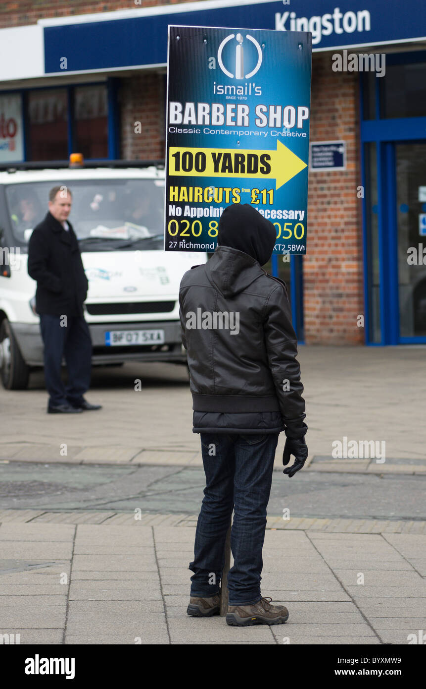 Uomo con un pannello pubblicitario al di fuori di Kingston, alla stazione ferroviaria di Londra Foto Stock Uomo con un pannello pubblicitario al di fuori di Kingston, alla stazione ferroviaria di Londra Foto Stock