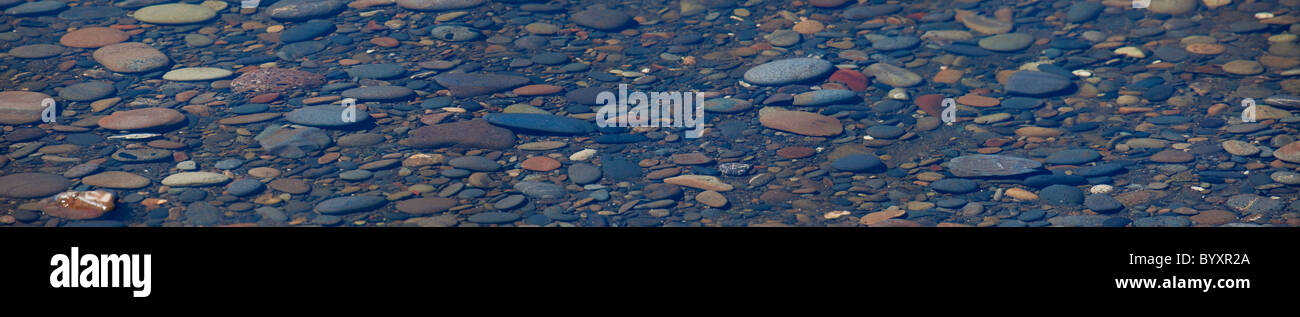 Si tratta di una panoramica delle pietre colorate in un letto a ruscello su una spiaggia oceanica. Foto Stock