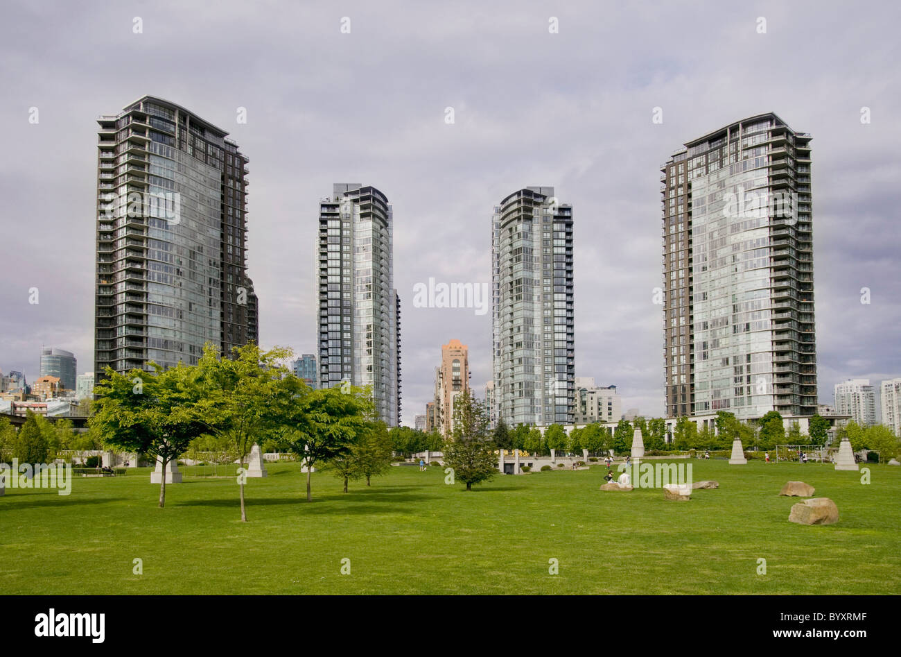 Alto edificio di quattro edifici con un parco verde in primo piano; Vancouver, British Columbia, Canada Foto Stock