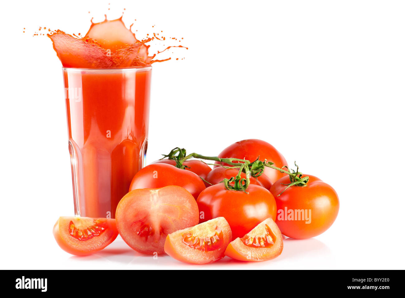 Succo di pomodoro. Pomodori maturi e un bicchiere di succo di pomodoro con splash isolati su sfondo bianco Foto Stock