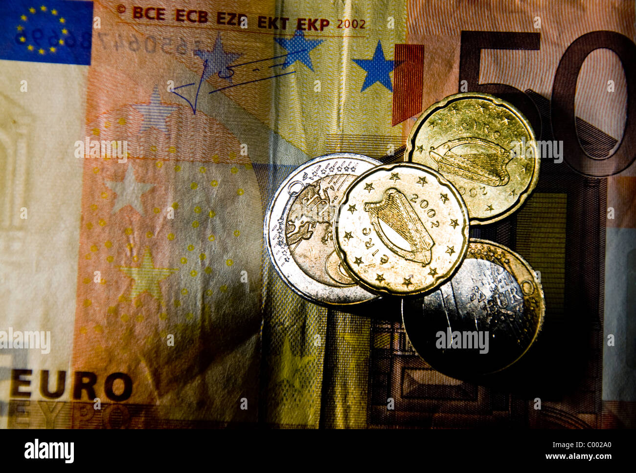 Monete metalliche in euro con l arpa irlandese simbolo poggiano su una cinquantina di euro nota Foto Stock