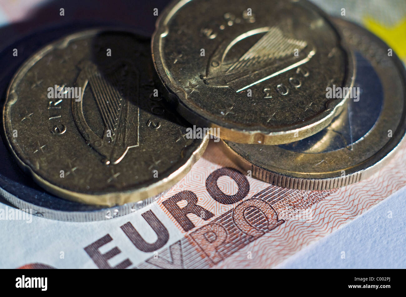 Monete metalliche in euro con l arpa irlandese simbolo poggiano su un fofty Euro nota Foto Stock