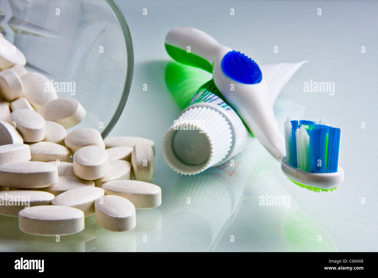 Compresse di calcio si versato da un vetro con dentifricio e spazzolino accanto a loro. Foto Stock
