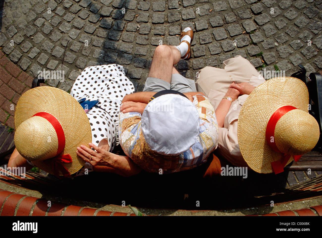 Il vecchio uomo seduto tra due donne anziane Foto Stock