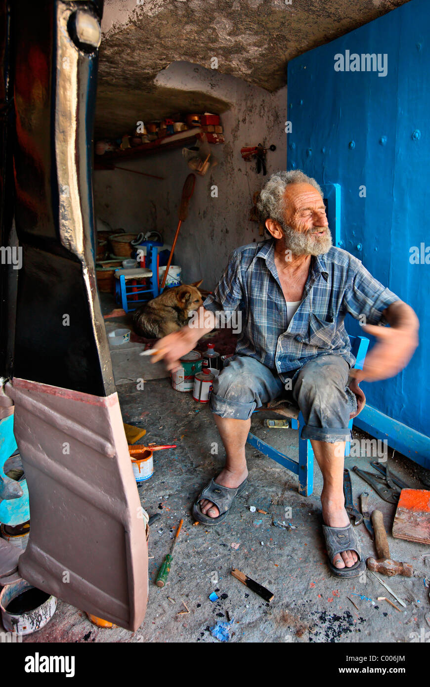 Un vecchio pescatore, descrivendo il mare dentro la sua 'syrma', Mandrakia village, isola di Milos, Grecia Foto Stock