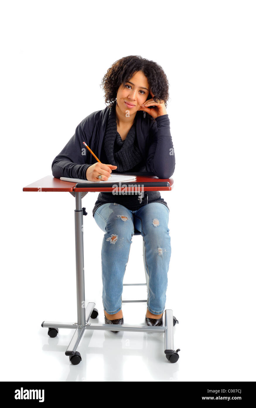 Bella femmina americano africano scuola studente iscritto nella classe alla sua scrivania Foto Stock