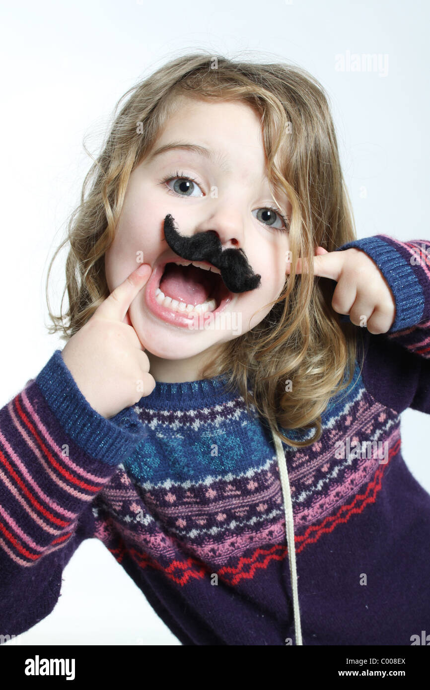 Un po' di bianco ragazza caucasica puntando al suo fake baffi neri, felice con la bocca aperta. Foto Stock