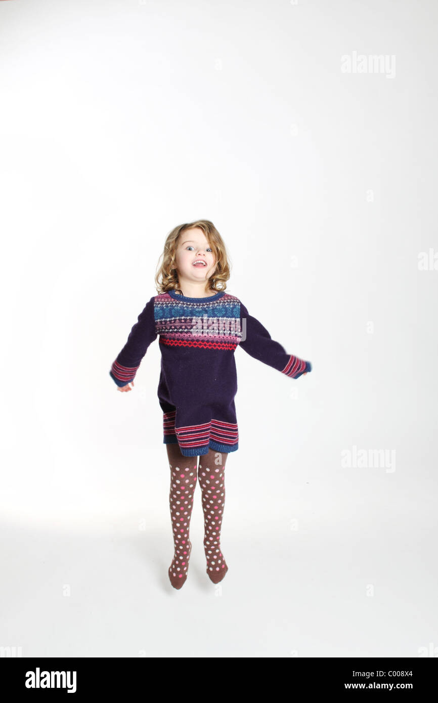 Poco quattro anno vecchia ragazza jumping in lana abito a ponticello Foto Stock