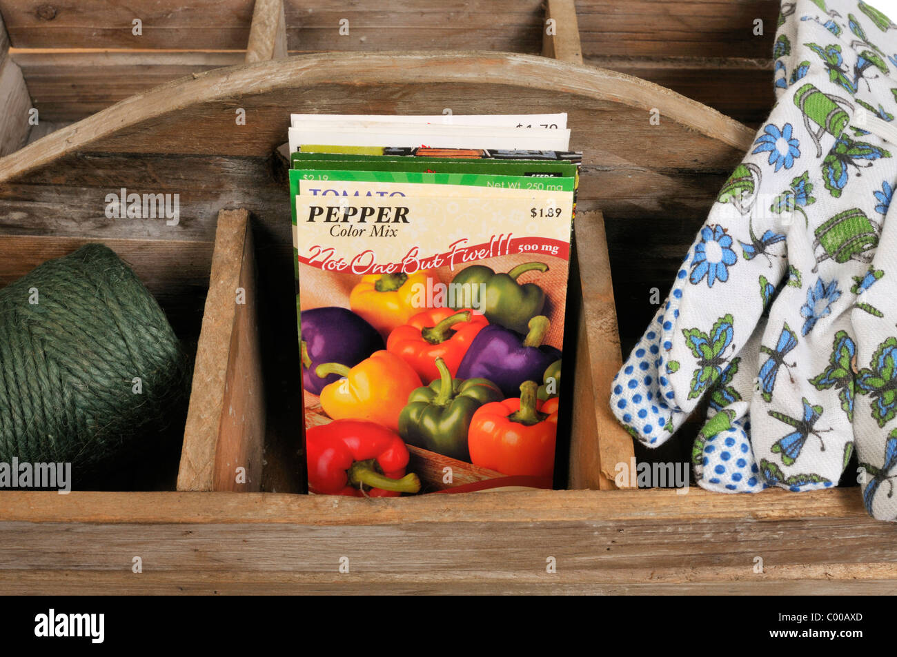 Pepe le sementi di ortaggi pacchetti nel vassoio in legno con guanti da giardinaggio e lo spago. Piantare i semi di ortaggi concept Foto Stock