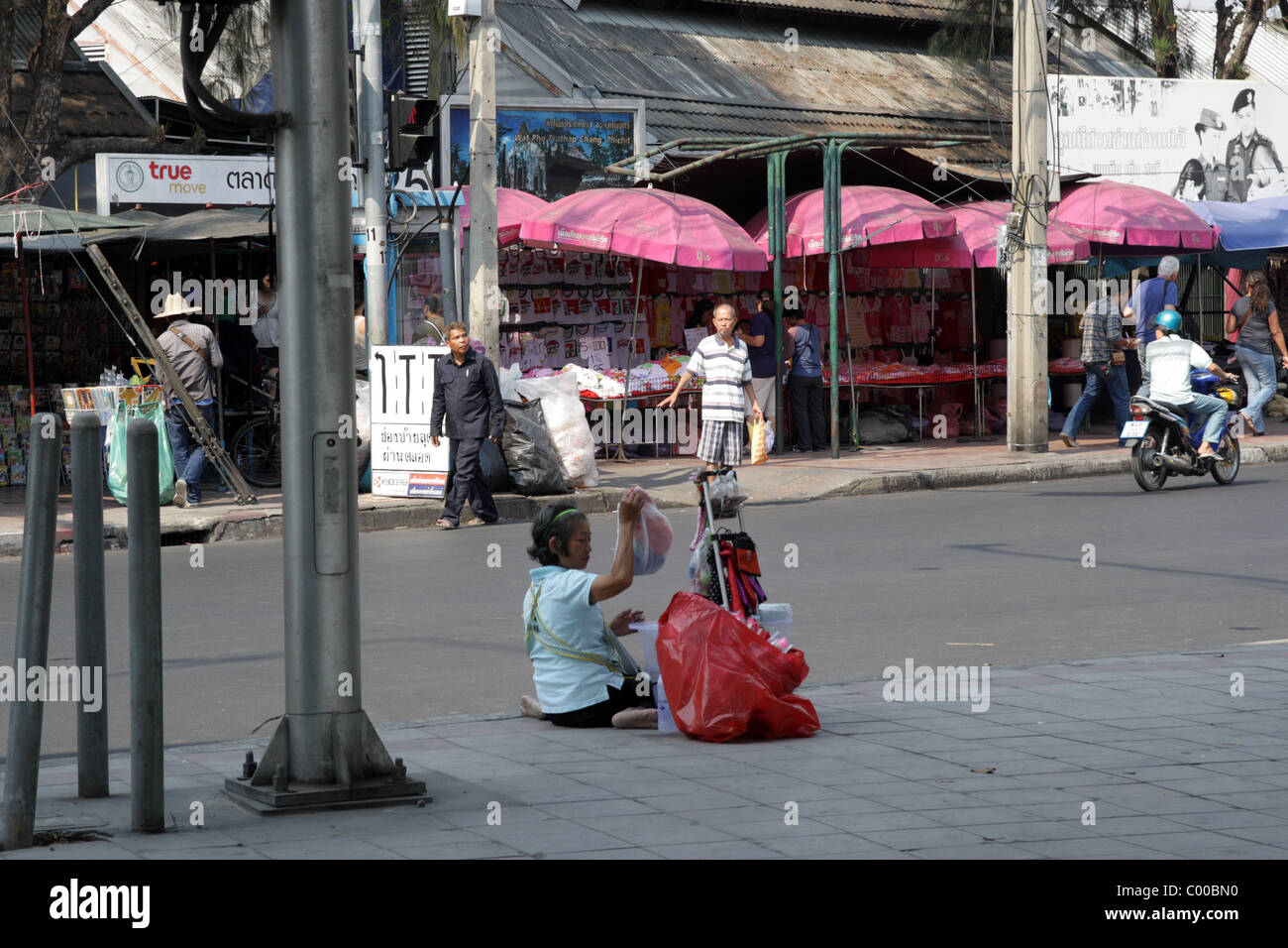 Vecchio mercante seduto sulla strada di Bangkok Foto Stock