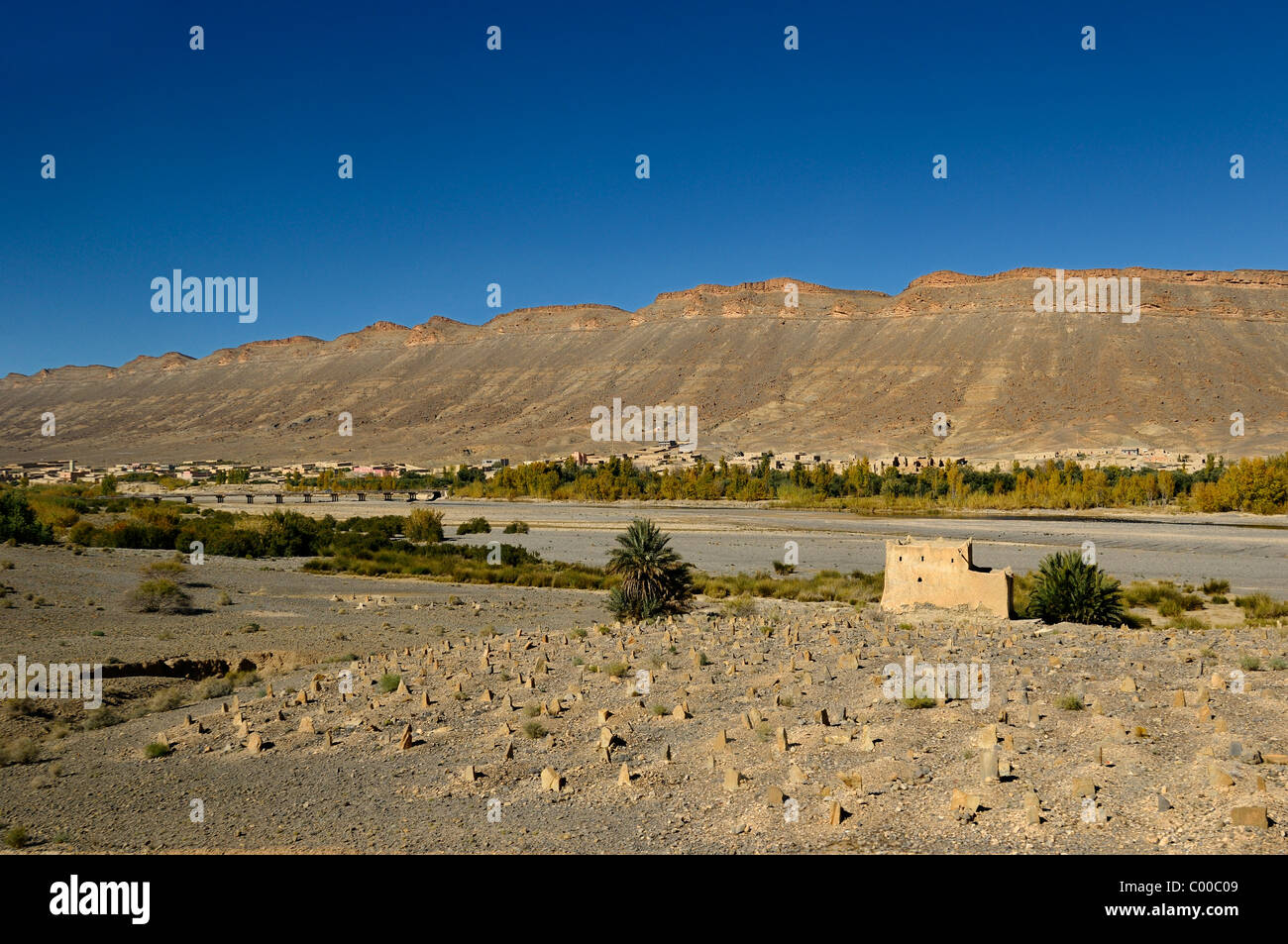 Il cimitero di berbera in terra arida lungo il fiume Ziz a ponte per Ait Khoujmani Marocco sotto il cielo blu Foto Stock