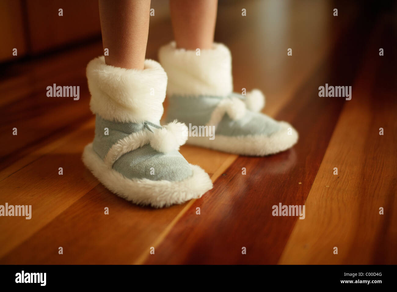 La ragazza caldo pantofole sul pavimento in legno realizzato da pelle di pecora sintetici Foto Stock