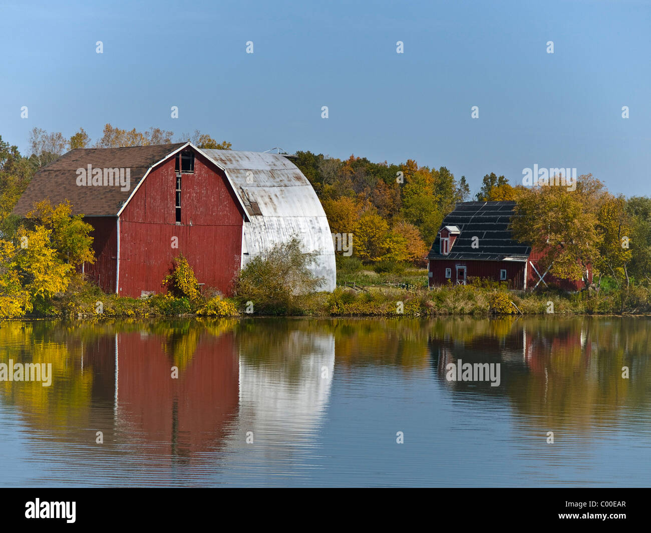 Antica fattoria di edifici con granaio rosso lungo la riva del lago Mott nella contea di Gennesse . Vi è una bella riflessione nel lago. Foto Stock