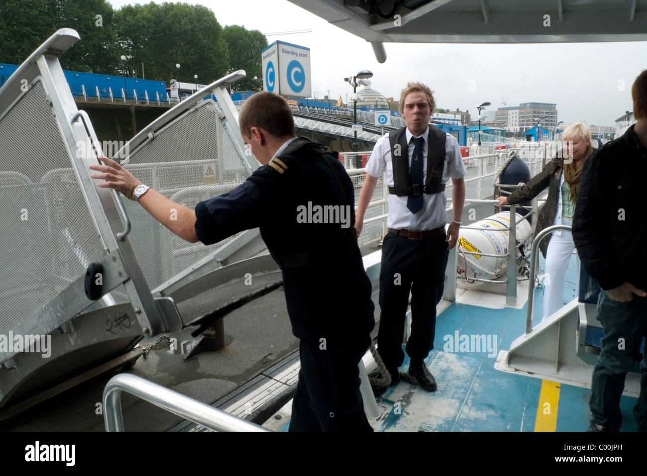 Giovani uomini al lavoro su un Tamigi ferry boat abbassamento rampa di imbarco per il carico di passeggeri a Greenwich a Londra England Regno Unito KATHY DEWITT Foto Stock