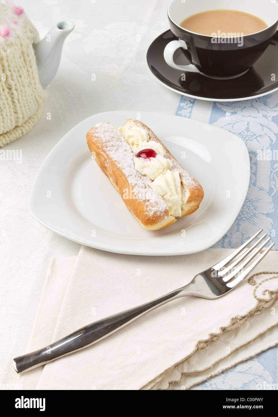 Il tè del pomeriggio con crema ciambella decorata con glace ciliegia. Foto Stock