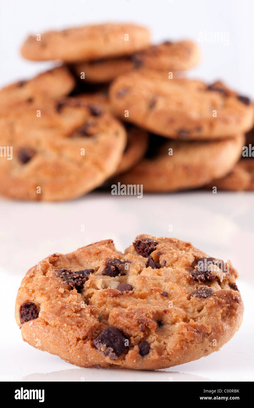 Close up di un Chocolate Chip Cookie con una pila di biscotti al cioccolato unsharp in background su bianco Foto Stock