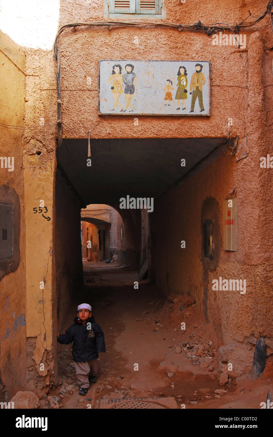 Algeria, Ghardaia, vista di un ragazzo che sta alla porta, guardando verso l'alto mentre un telaio verniciato visualizzati sulla parete al di sopra della porta Foto Stock