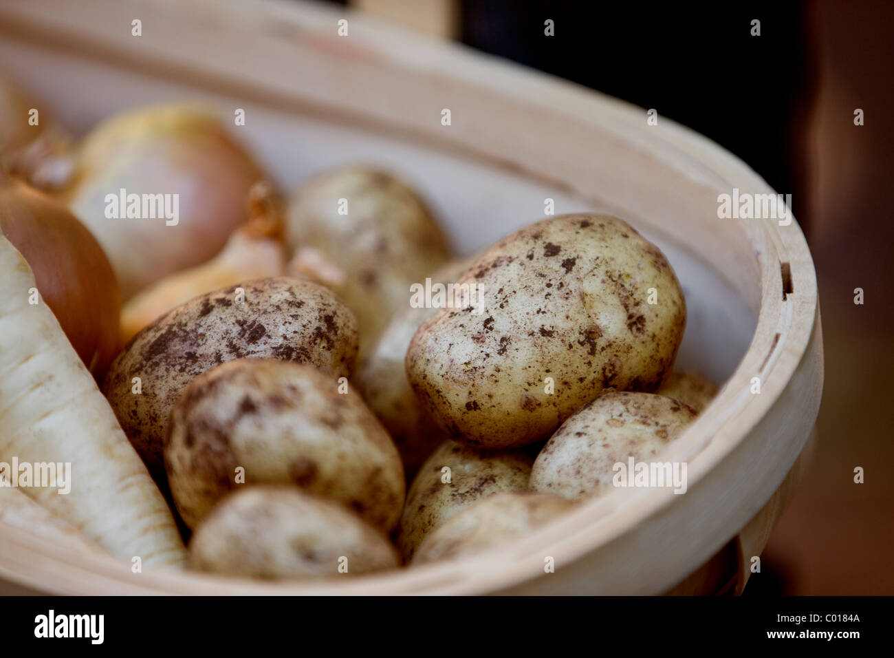 Patate, pastinaca e cipolle in un trug Foto Stock