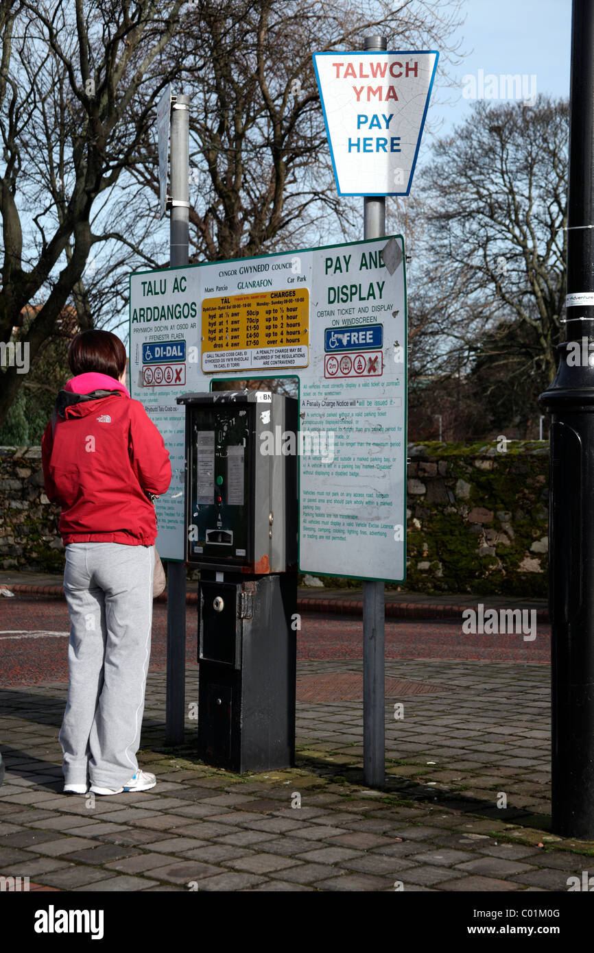Giovane donna a pagare e visualizzare Ticket Machine, Bangor Foto Stock