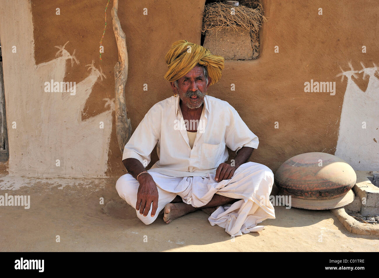 Anziani testa di uomo con turbante seduto di fronte alla parete dipinta di casa sua, deserto di Thar, Rajasthan, India, Asia Foto Stock