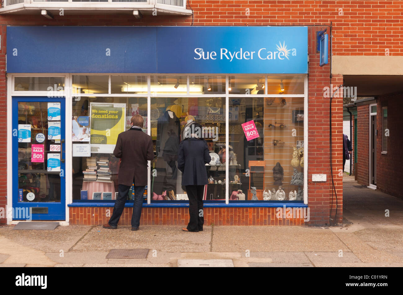 Un paio di window shopping in una carità shop store in Aldeburgh , Suffolk , Inghilterra , Inghilterra , Regno Unito Foto Stock