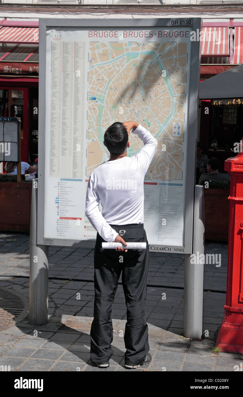 Un uomo la visualizzazione di una mappa di Bruges in piazza Zand, Bruges (Brugge), Belgio. Foto Stock