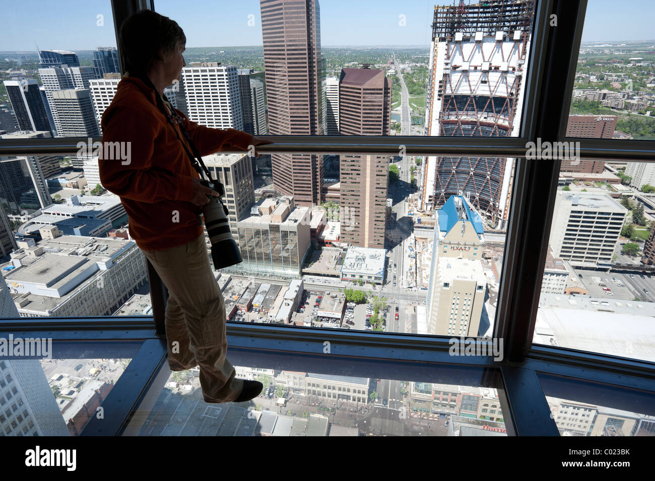 Donna in piedi sul pavimento di vetro del ponte di osservazione nella torre di Calgary in Canada. Foto Stock