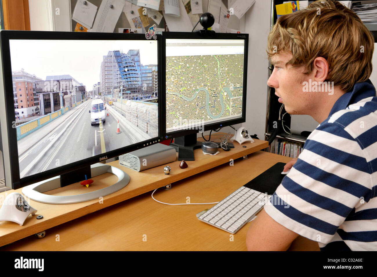 Giovane uomo guardando le immagini della città su Google Street View visualizzata sullo schermo di un computer Foto Stock