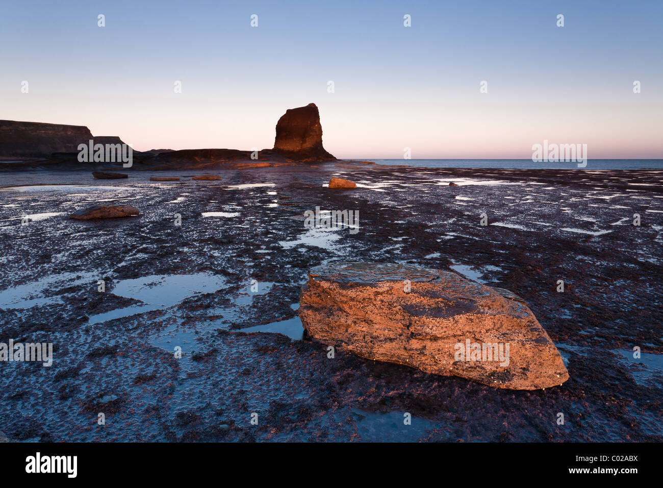 Bassa sun all'alba Saltwick Bay nel North Yorkshire. Foto Stock