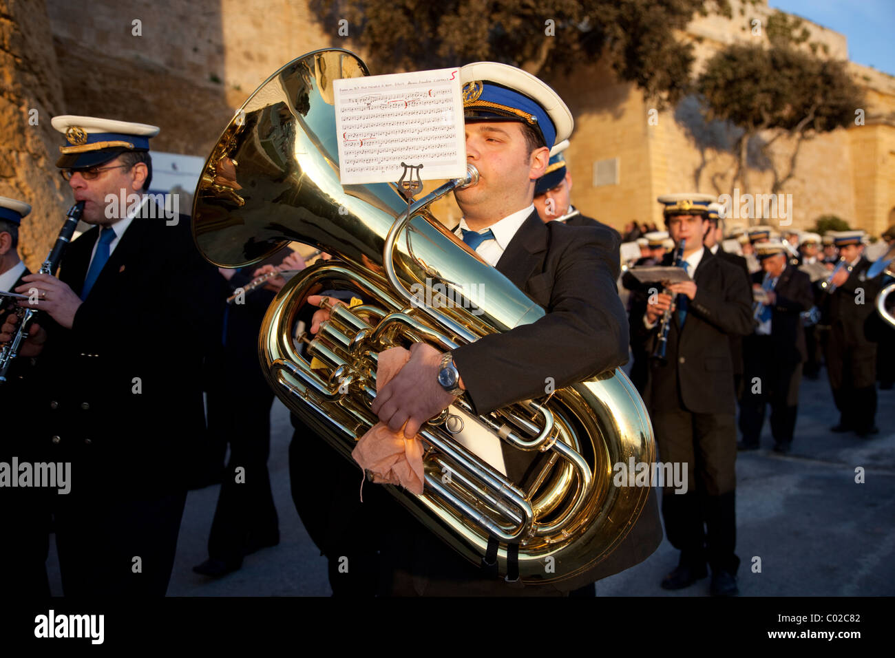 I membri di una banda di ottoni in abiti scuri, riproduci musica durante la street parade che commemora il Venerdì Santo che si terrà a Malta. Foto Stock